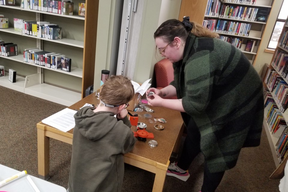 Nicole Labrie, Bonnyville library manager, helps kids make their buttons during comic book day.