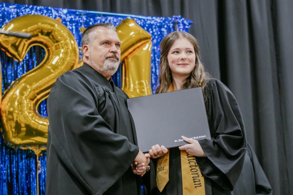 Valedictorian Peyton deMoissac accepts her portfolio from Principal Mark Tichkowsky.