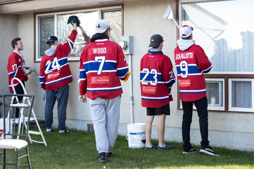 A group of Jr. B hockey players clean windows at Heritage Homes, in St. Paul, Oct. 6. Janice Huser photo.