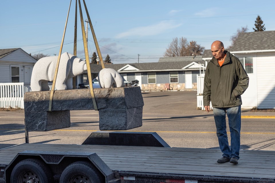 Stewart Steinhauer helps guide a bear sculpture into place in front of Portage College in St. Paul, on Friday.