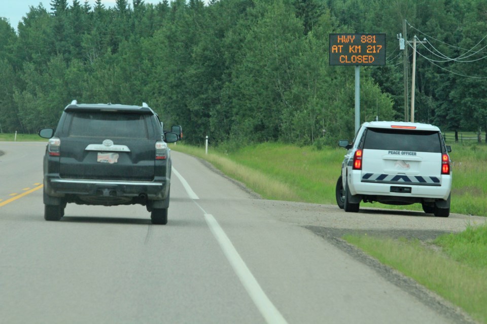 A Lac La Biche County peace officer patrols near a highway sign advising motorists of a crash further north on Highway 881.    Image: Rob McKinley