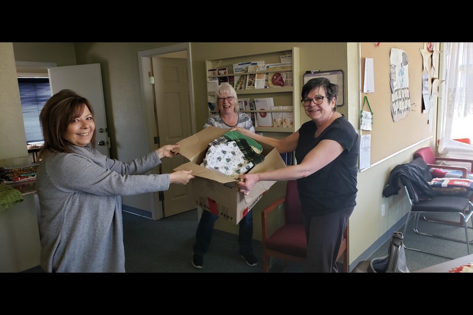 Plamondon Quilters president Rachelle Lemay (right) and member Shirley Michaud (middle) have been buys in the last few weeks. The have helped to create 100 bags to carry medical uniforms and delivered 50  locally-crafted "Joey" bags to the local humane society, accepted by society director (left) Stacey Dease.
