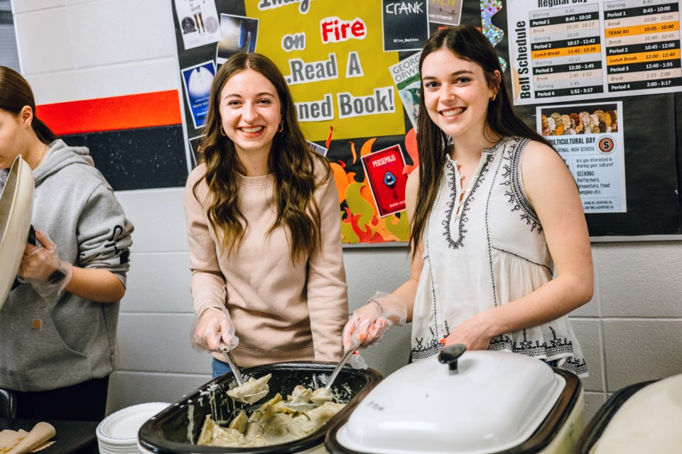 Kalli Foisy and Karlee Blain help serve hundreds of perogies to fellow students at the St. Paul Regional High School multi-cultural day celebration on May 13. 