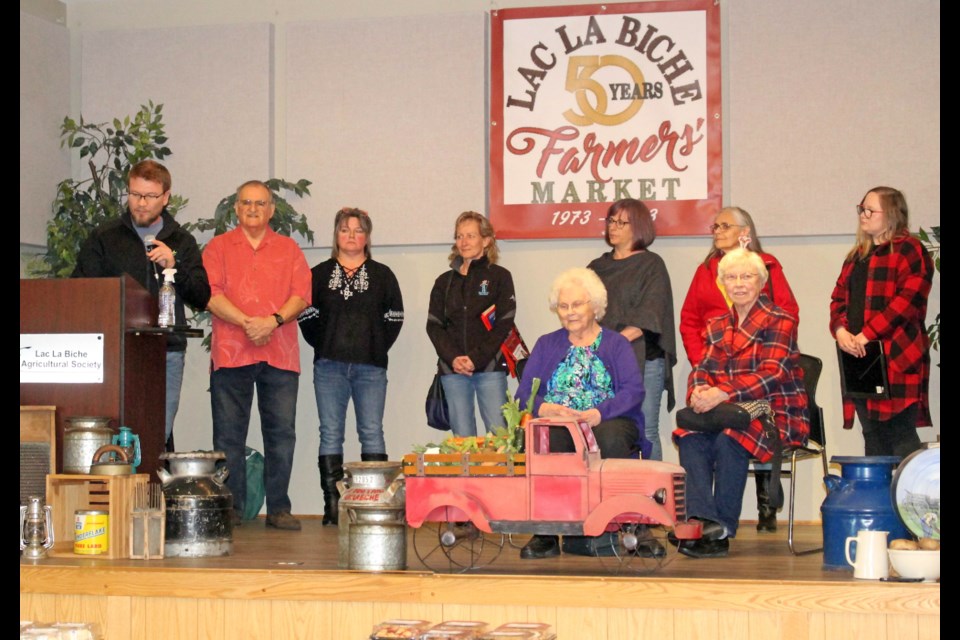 Two of the founding members of the Lac La Biche Farmers' Market, Freda Phillips and Cathy Lawson sit on stage at the Lac La Biche Agricom last Friday afternoon, surrounded by local and regional officials helping to celebrate the golden anniversary of the market.