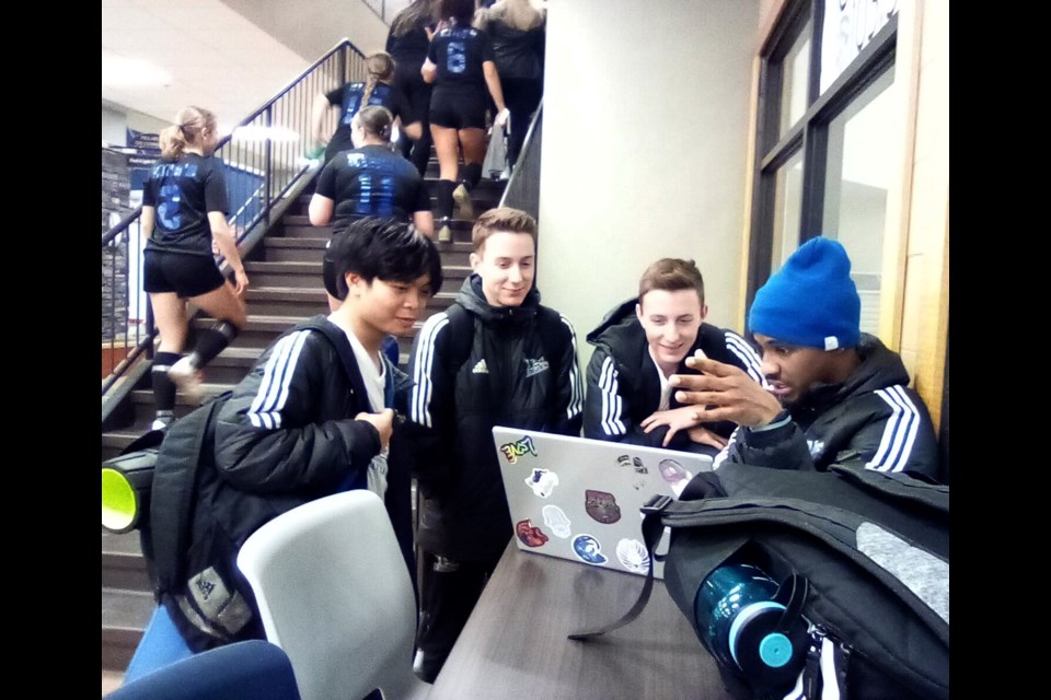 It isn't all "futsal, futsal, futsal" at the Alberta College's Athletics Conference Futsal regional playdowns taking place at Lac La Biche's Bold Center from Jan 19-21 ... these are student-athletes, so there's some studying happening too.
Here, between games on Friday night, Kings University Eagles players (l-r) Psalmuel Realon and brothers Noah and Jules Leggo help teammate Akil Johnson with some biology homework. Johnson, who was at Portage College last year, is taking Interdisciplinary Sciences at TKU. The weekend saw more than 200 student-athletes from men's and women's post-secondaries across northern Alberta competing. Image- Rob McKinley.

