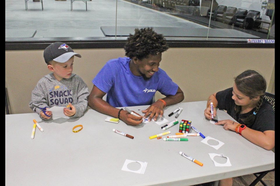 Akil Johnson of the Bold Center assists Jackson Buchko and Hala Kalaban in making secret agent IDs.  