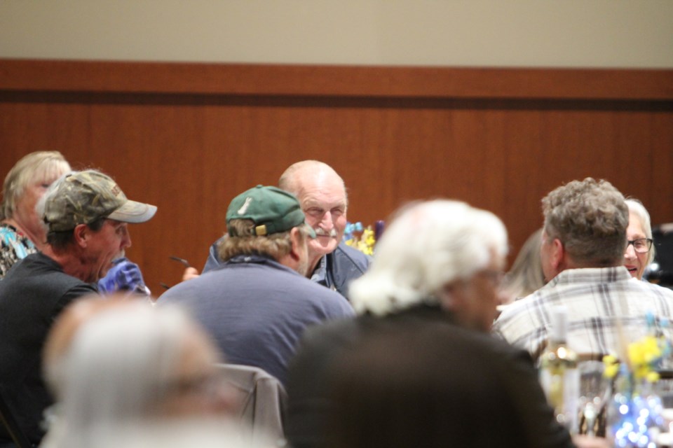 Alex Broadbent laughs with friends at a table  at the recent Agricultural Appreciation fundraiser. Broadbent is a farmer and former municipal elected official 