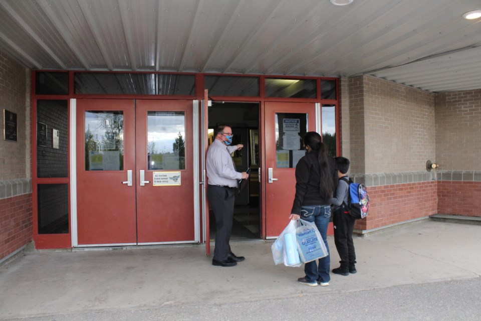 Aurora Middle School Principal Conal Donovan welcomes a young student and his mom to the first day of classes. Parents were encouraged to bring new middle school students into the school to make the transition from elementary school a little easier.    Image: Rob McKinley