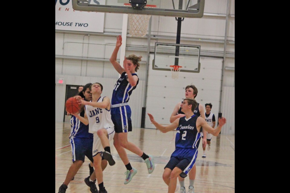 JAWS JV Shark Ian Gagnon (9) tries to go up for the hoop with Assumption defenders blocking.