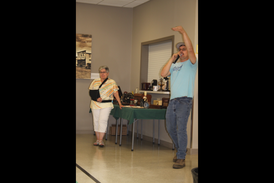 Cake auctioneer looks for some sweet deals as helper Alice Thompson gets ready with another tasty item.