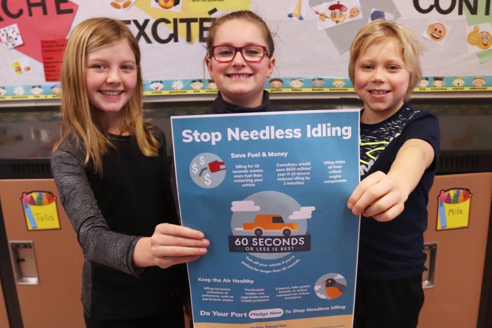 (left to right) Avery Crook, Kathryn Graham, and Brady Fox, show off one of the posters they're using to explain the impacts idling your vehicle can have on the environment. Photo by Meagan MacEachern.