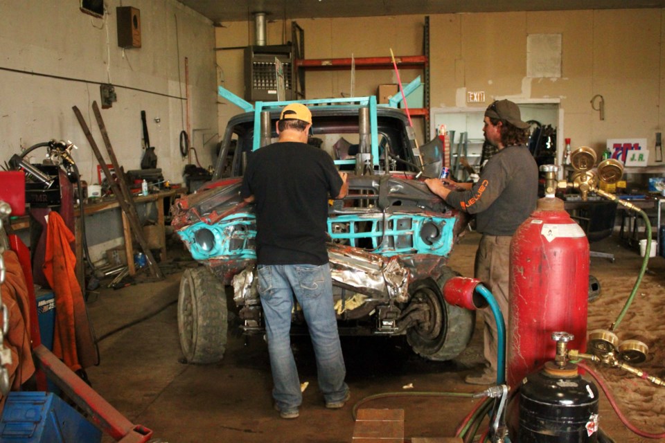 from the left: Dan Cote and his son Derek Cote together in the shop working on derby vehicles.
