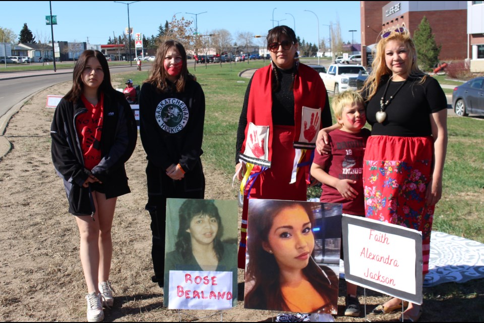 Amy Desjarlais (right) and Kady Desjarlais (centre) stand next to photographs of Faith Jackson, their cousin, and Rose Berland, the grandmother of their children. Joining them at the MMIW Photo Memorial was Amy's children Laianna, Adrianna and Austin Berland.