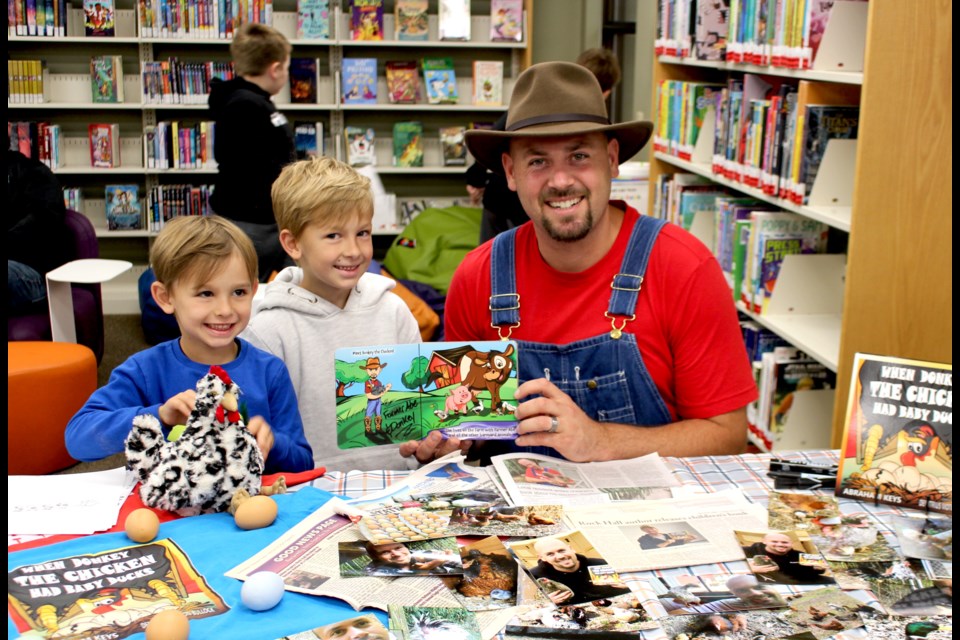 Local residents Ivan and Adam Dander take a photo with children's book author Abraham Keys who held a reading of his debut book When Donkey The Chicken Had Baby Ducks at the Bonnyville Municipal Library on Aug. 10.