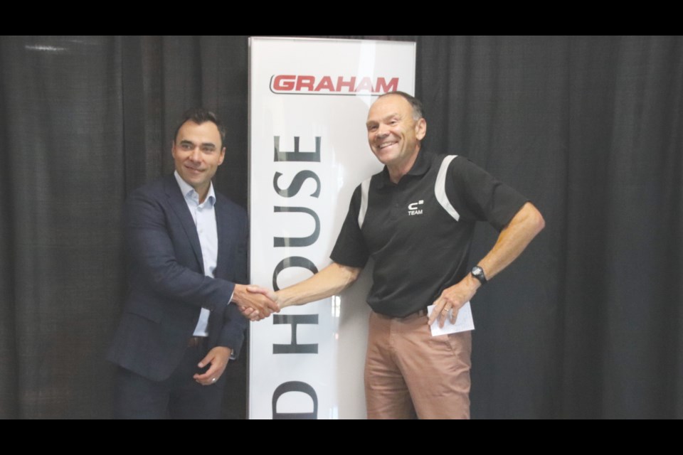 Graham Construction vice president Shawn Jubinville shakes hands with C2 general manager Les Parsons over the agreement to rename the field house the Graham Field House for a period of five-years.