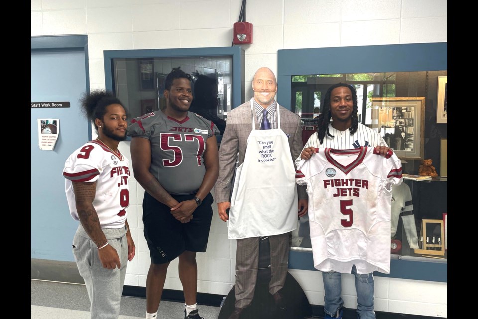 Cold Lake Fighter Jets players Branden McCraney, Patrick Jones Jr., Jayde Rowe (left to right), take an opportunity to pose with H.E. Bourgoin Middle School's unofficial mascots,  Dwayne Wade 'The Rock' Johnson 
