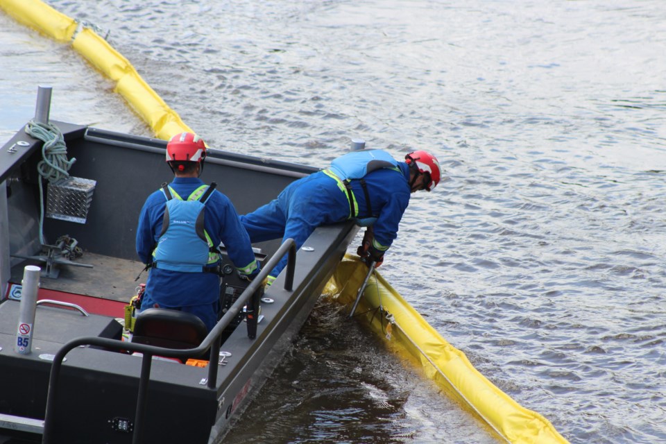 Teams of two on boats and on land worked together to practice containing an oil spill on the Beaver River.