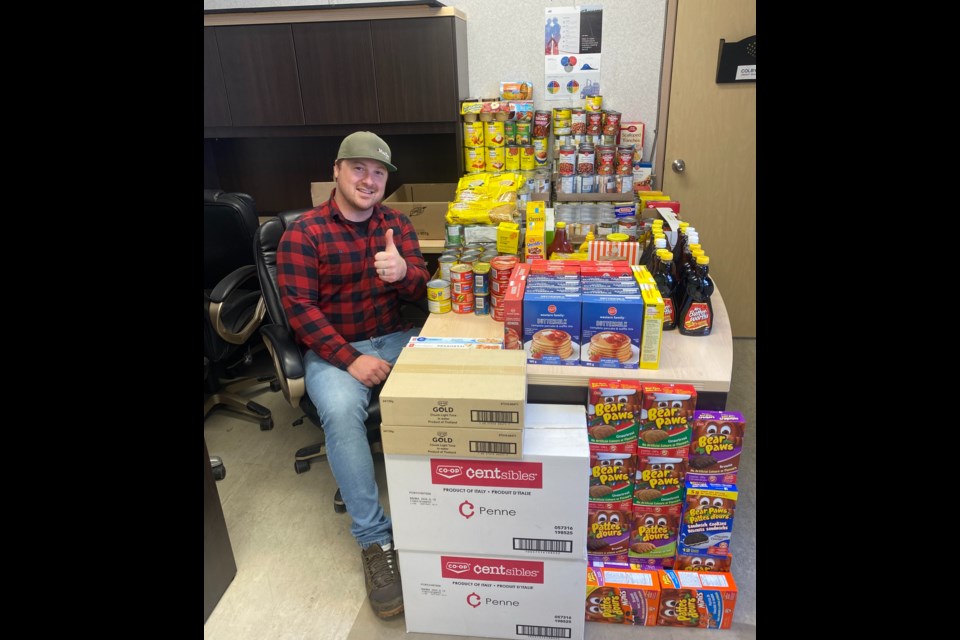 Colby Wrobel, project manager for MasTec Canada, sits next to a portion of the 983.77 lbs of food donations collected with the help of Bonnyville businesses. 