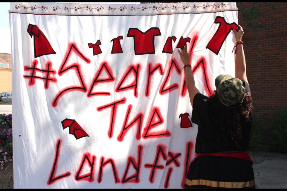 Sîpihko Kamâmak (Blue Butterfly) pins red dresses to a sign hanging out front of the Bonnyville Provincial Building during the Search the Landfill Red Dress Rally held on Sunday. Sîpihko Kamâmak spent 32 days between the two camps, Camp Morgan located next to the road to Prairie Green Landfill, and Camp Marcedes, which is located next to the Canadian Museum for Human Rights, also in Winnipeg. The camps are named after the victims of the alleged killer Jeremy Skibicki.