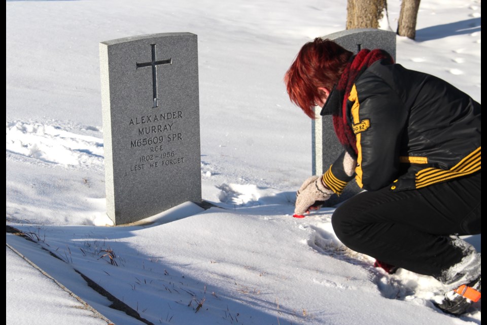 Grade 12 École Notre Dame student Kaitlyn Justus lays a poppy between two headstones of local men who served the Canadian Armed Forces. 