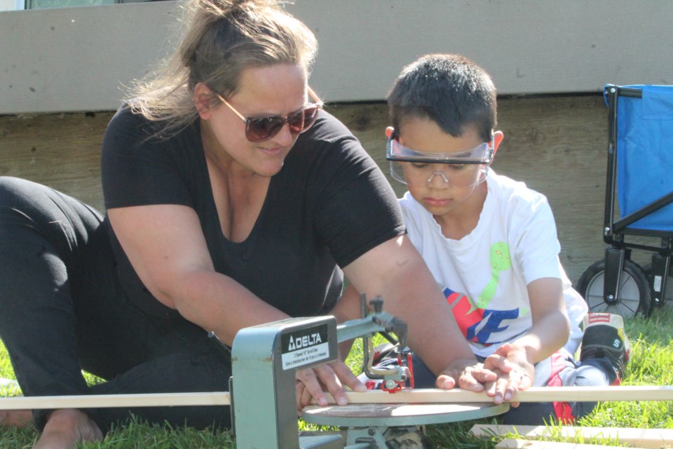 FCSS's Conny Fechner helps youngster Liander Beland line up the cut of his ladder ball posts during the recent family event at McArthur Place