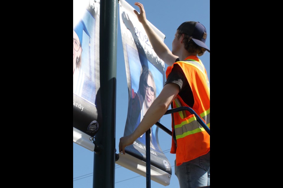Staff from Lac La Biche County's Department of Parks and Open Spaces have been busy in the days leading up to weekend graduation ceremonies at Ecole Plamondon School and J. A. Williams. On Thursday, county staffer Patrick Dulmage was part of a crew attaching grad-picture banners to the light-posts along Beaver Hill Road. The banners have been placed in Lac La Biche and Plamondon, and feature graduating students from the Lac La Biche Off Campus School, Ecole Beausejour, Light of Christ, Ecole Plamondon and JAWS.    The JAWS and Ecole Plamondon convocation ceremonies take place on June 24. Graduating students from Off Campus will be part of the JAWS ceremony.  Ecole Beausejour and Light of Christ convocation ceremonies were held in June.