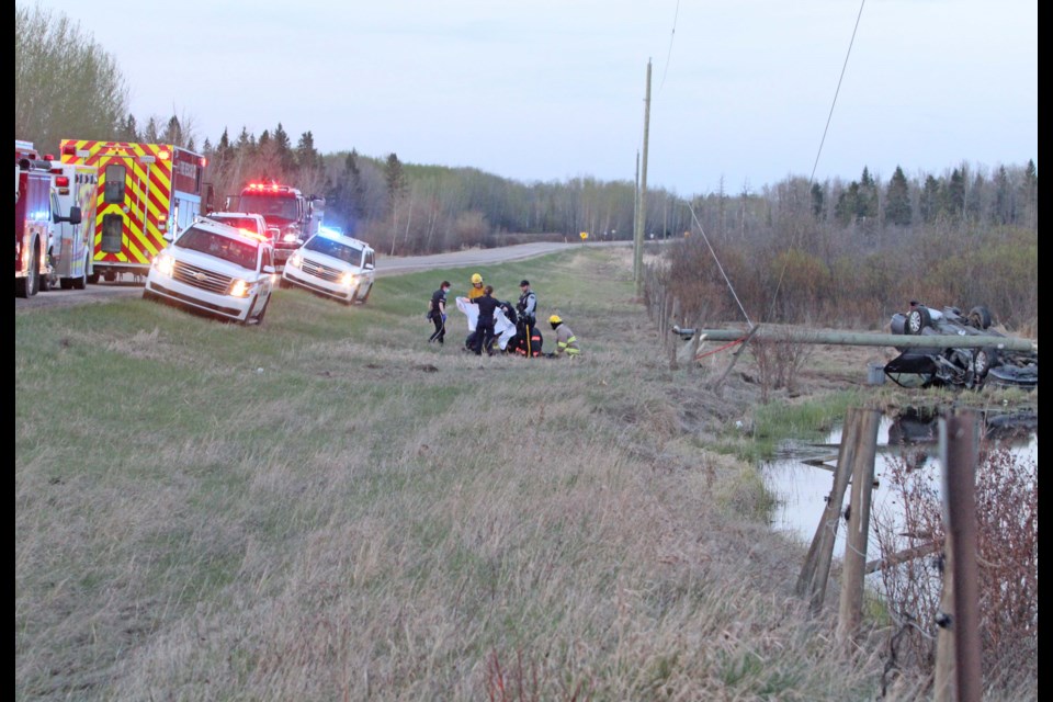 Lac La Biche and Hylo fire crews, RCMP, peace officers and EMS attend to the occupants of a car that ended up about 100 feet from the road, and just feet from a roadside dugout in Friday night's crash.
