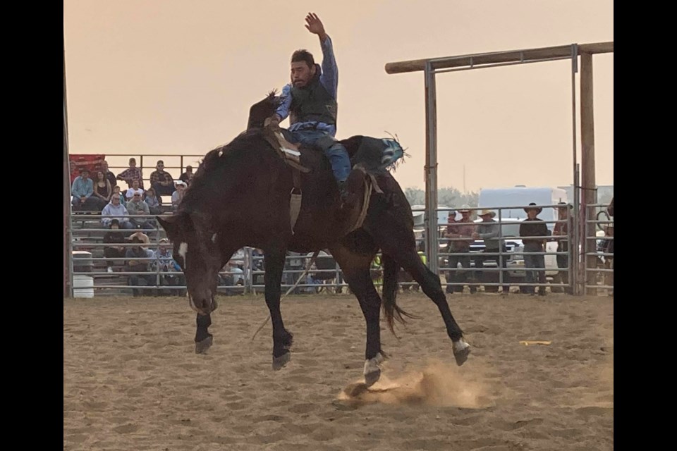 Sunset ride. A bronc rider is back-lit by a smoky Friday night as the first night of the Lakeland Country Fair's opening-night rodeo went well past dusk.