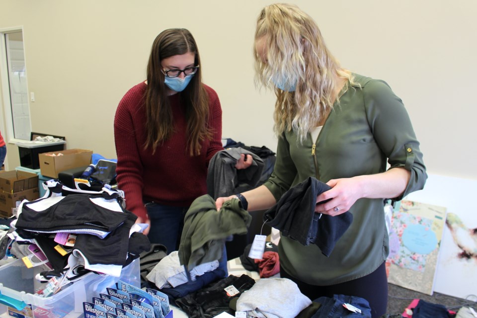 (left to right) Katelyn Chatel and Whitney Arcand organize the clothes that were donated for the Hospital Care Kits. Photo by Robynne Henry.