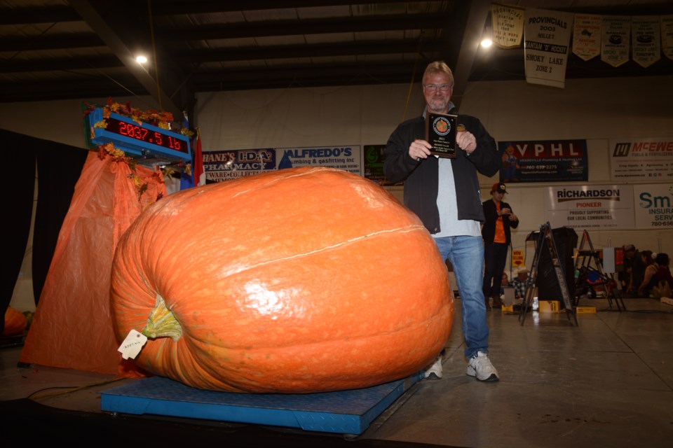 Don Crews holding his first-place plaque, with his big pumpkin on the scales just a minute or two after it was weighed, showing the weight on the readout of 2,037.5 lb
