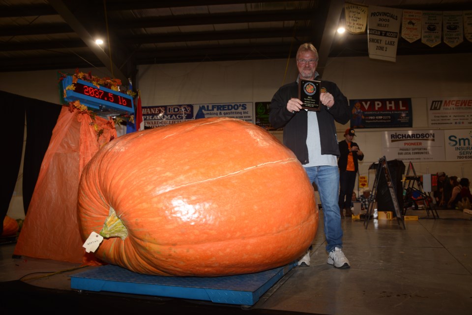 Don Crews holding his first-place plaque, with his big pumpkin on the scales just a minute or two after it was weighed, showing the weight on the readout of 2,037.5 lb