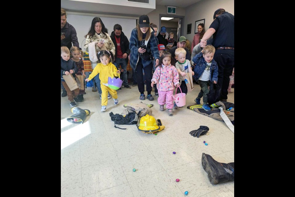 Four to six-year-olds gather up eggs with firefighting gear scattered in the room.