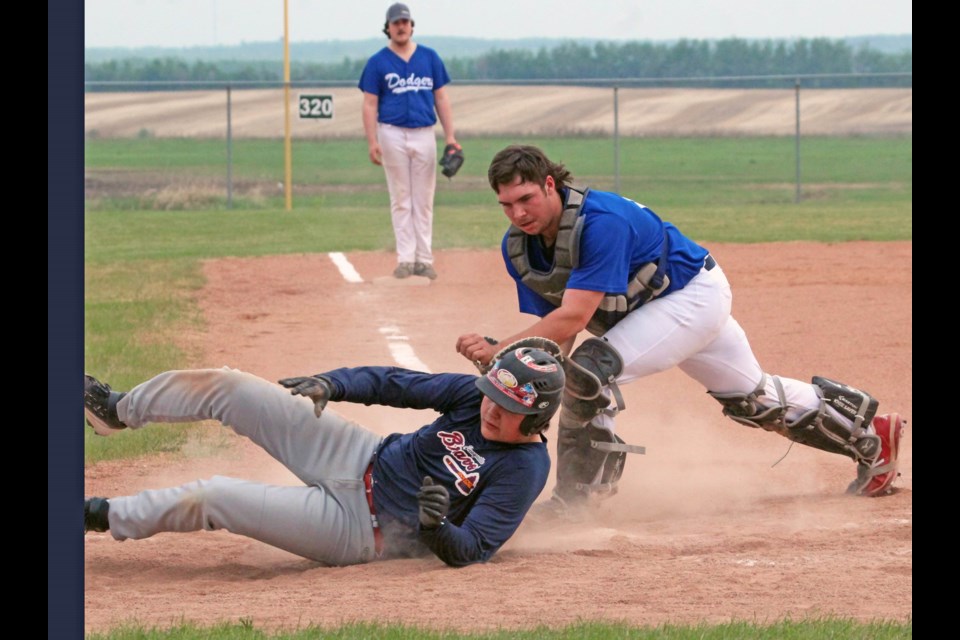 Bonnyville Braves U18 player Gunnar Tomm rolls across home plate as Lac La Biche Dodgers catcher Ethan Walgren tries for the tag during Thursday night's Lakeland Minor Ball action at the Bonnyville diamonds. The Braves beat the Dodgers 10-8.  The two teams will play again over the coming weekend at a league mini-tourney in Elk Point.