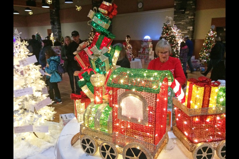 Festival of Trees founding volunteer Claudette Dube adjusts one of the 65 festive displays in the 'tree room' on Saturday.