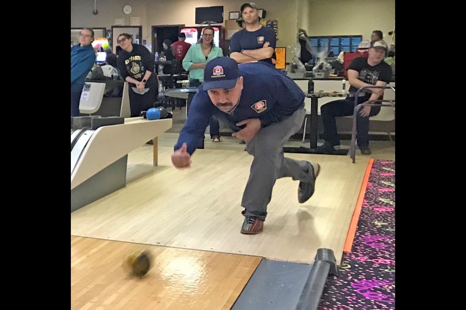 Lac La Biche County firefighter Ivan Alvarado takes aim as his teammates watch during Friday night's Bowl For Kids' Sake.