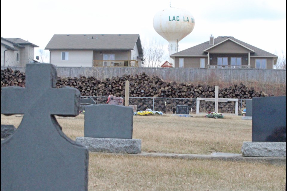 A large pile of railway ties stretches along the fenceline of the Lac La Biche cemetery and a residential subdivision near the water tower. The chemically-coated railway ties are on CN Rail property.