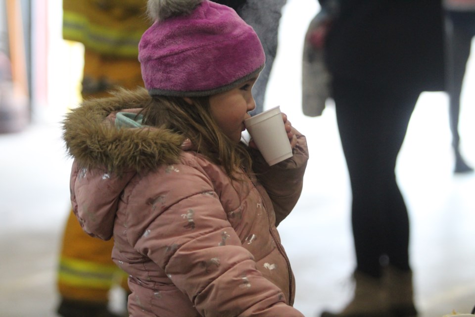 Allie Larock enjoys a cup of hot chocolate as she waits to have her photo taken with Santa