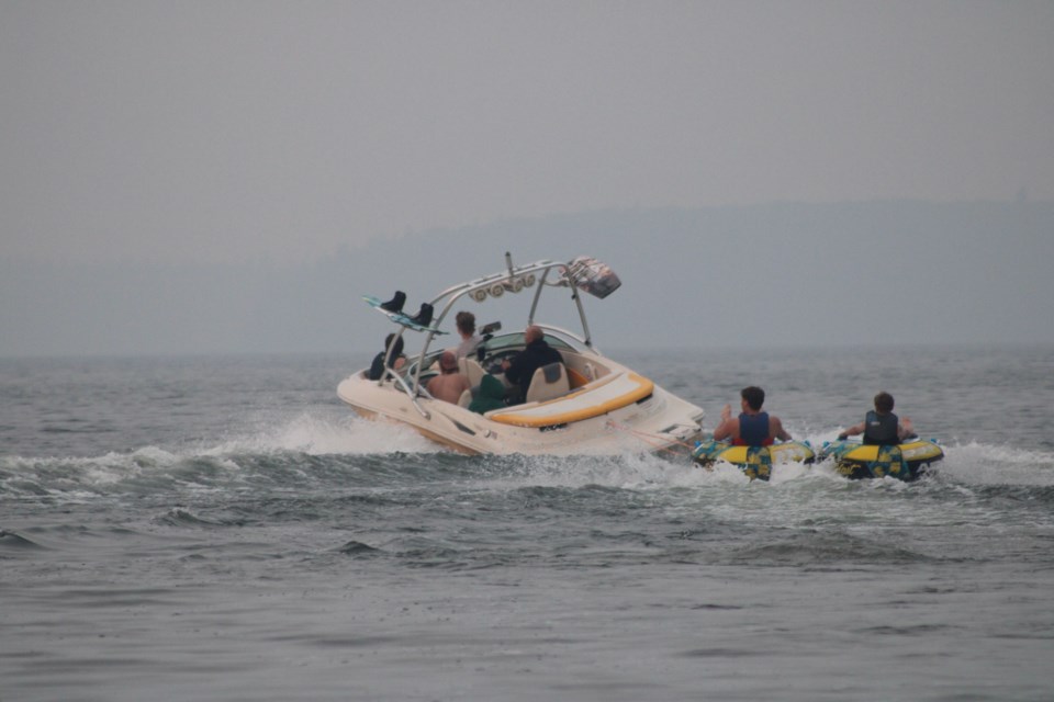 The smoke-hazy shoreline of Pinehurst Lake is barely visible on Saturday afternoon as a crew of boaters enjoy some Lakeland recreation, despite the smoke.