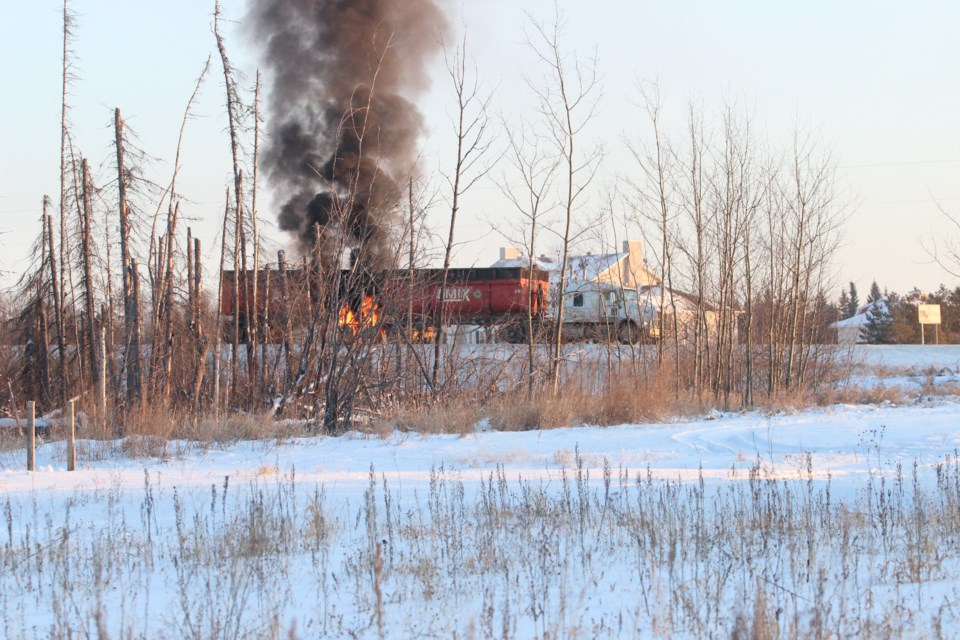 Smoke and flames roll out from the underside of a trailer along the bypass road