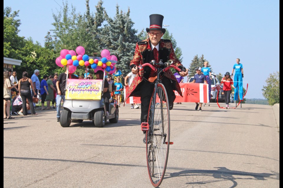 Flyin' Bob Palmer on his penny-farthing bike leads the Flyin' Bob's Circus Camp entry in Friday's Summer Days parade. The 90-minute long parade had about 50 floats.  Image - Rob McKInley