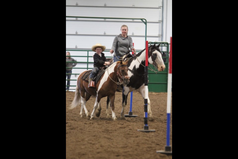 Cooper Plamondon on the leadline gets help around the pole bending course from Jodie Plamondon