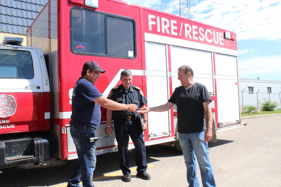 Buffalo Lake Metis Settlement's Roy Auger makes a ceremonial tranfer of a dollar to Lac La Biche County councillor Colin Cote and regional fire chief John Kokotilo to finalize the deal.
