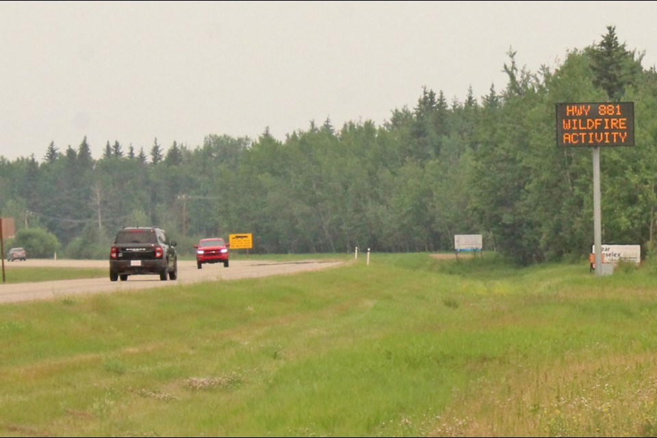 Muted light and smoky skies south of Lac La Biche on Friday morning as motorist pass a posted travel advisory due to wildfires in the area.