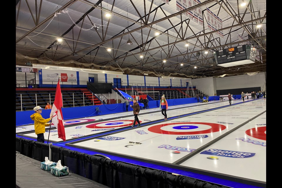 Crews work on getting the ice ready, while youth do a rehearsal for opening ceremonies.