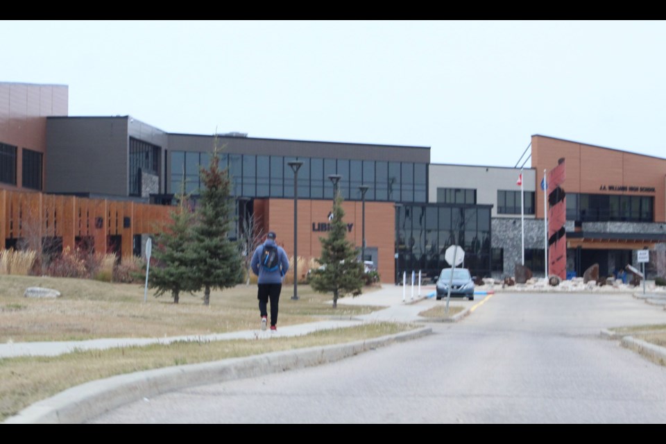  A person walks towards the Lac La Biche Bold Center on Wednesday. The facility is connected to the high school where threats were directed earlier in the week. Police have investigated the incidents and made arrests, but online accusations have continued, singling-out people some think are involved.