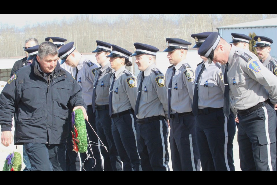 Lac La Biche County's Manager of Protective Services and Regional Fire Chief John Kokotilo carries a wreath past peace officer cadets and Community Peace Officers at a Lac La Biche tribute ceremony for two slain Edmonton Police Service members.