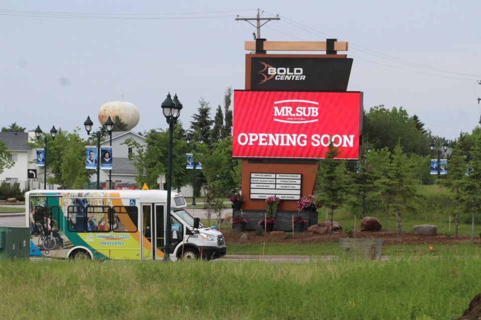 A municipal shuttle bus rolls past the Bold Center sign announcing a new food court addition.