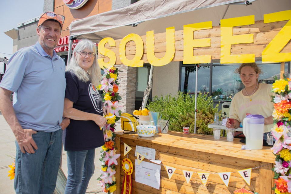 George Kowalchuk (left) and Monica Rosychuk (middle) from Willingdon purchase lemonade from the Squeez Lemonade Stand.