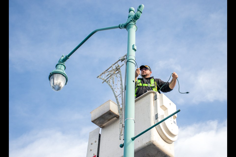 Kirk Thornton with the Town of St. Paul installs Christmas lights just outside the St. Paul Journal office on Nov. 27.
