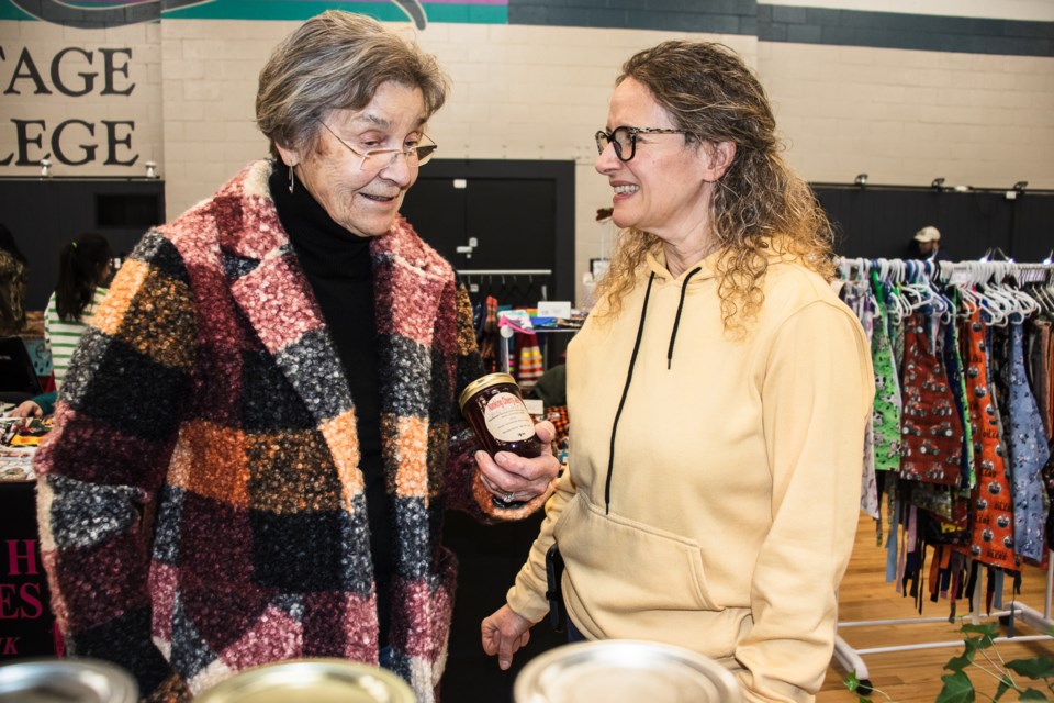 Louise Plante (left), who kick-started the St. Paul Farmers Market back in 1974, speaks to Monique Bardal about a merchandise.